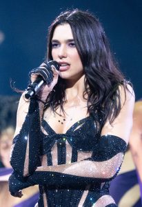 Dua Lipa ερμηνεύει το τραγούδι «Nothing Compares 2 U» στη σκηνή του Aviva Stadium στο Δουβλίνο, φορώντας λευκή δαντελένια ολόσωμη φόρμα.